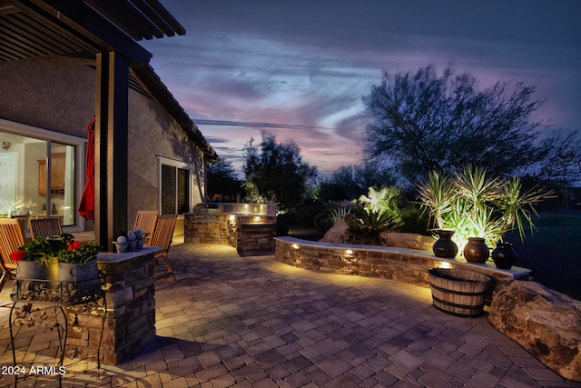 patio terrace at dusk featuring an outdoor kitchen