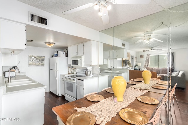 kitchen featuring white appliances, sink, a textured ceiling, white cabinets, and dark hardwood / wood-style floors