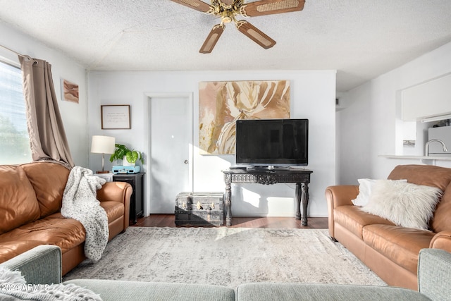 living room with ceiling fan, wood-type flooring, and a textured ceiling