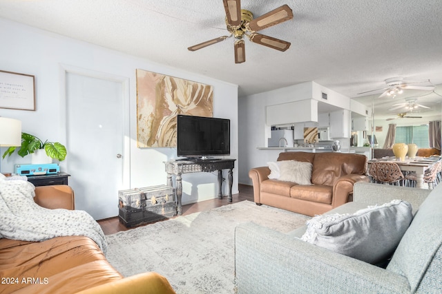 living room with dark wood-type flooring, a textured ceiling, and ceiling fan