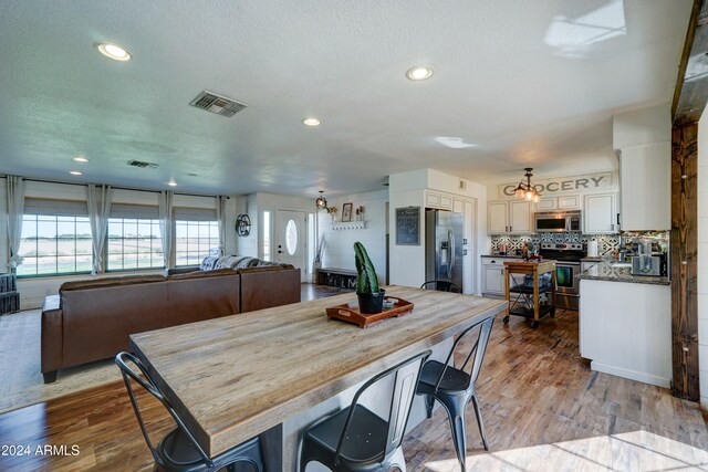 dining area with a textured ceiling and light hardwood / wood-style floors