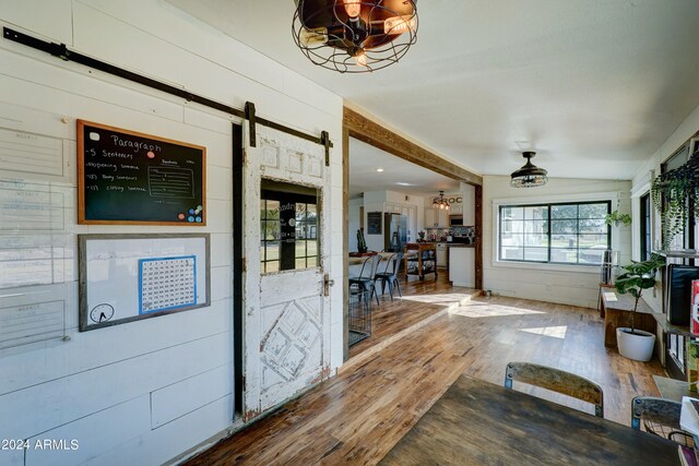 interior space with vaulted ceiling, an inviting chandelier, a barn door, and hardwood / wood-style floors