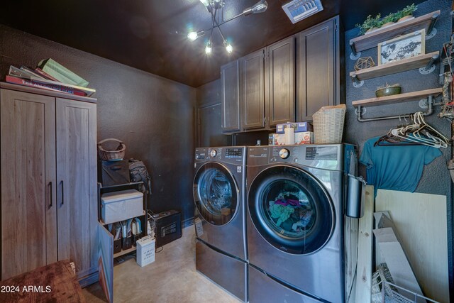 clothes washing area featuring a notable chandelier, washing machine and dryer, and cabinets