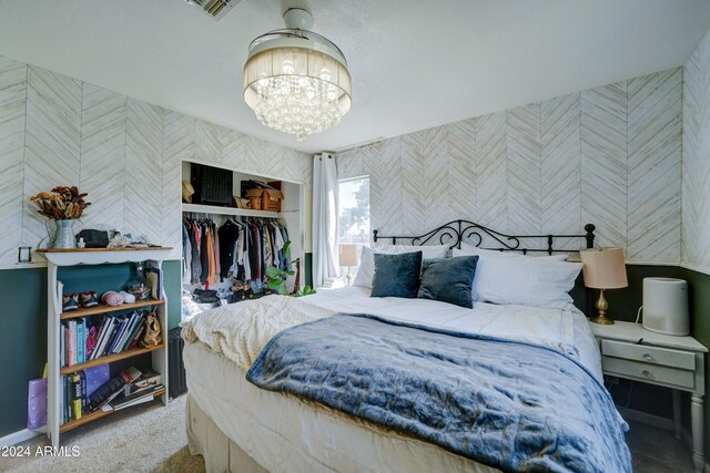 carpeted bedroom featuring a closet and a notable chandelier