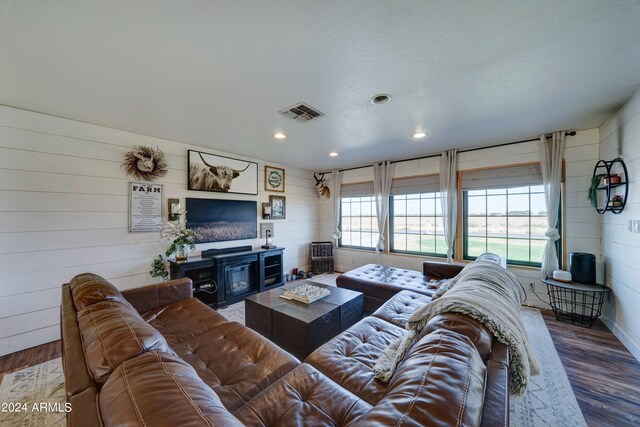 living room with wood walls, hardwood / wood-style floors, and a textured ceiling