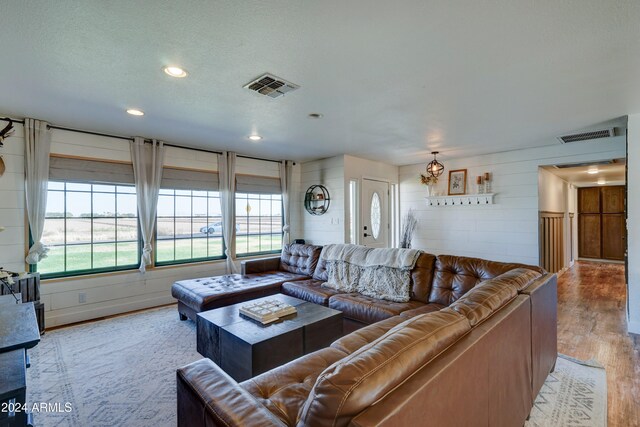 living room with a textured ceiling, a healthy amount of sunlight, and light hardwood / wood-style flooring