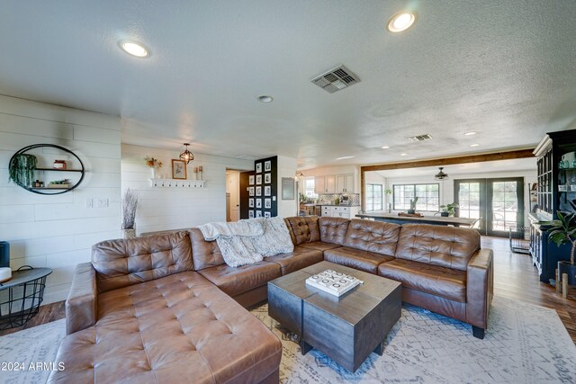 living room featuring french doors, light wood-type flooring, and a textured ceiling