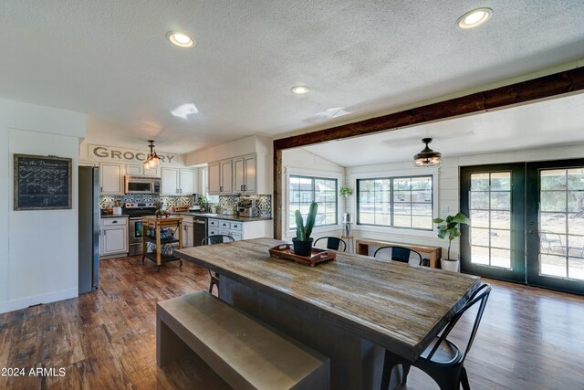 dining room with a textured ceiling, lofted ceiling with beams, french doors, and dark hardwood / wood-style flooring