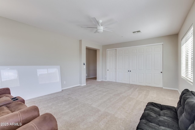 carpeted living room with baseboards, a ceiling fan, and visible vents