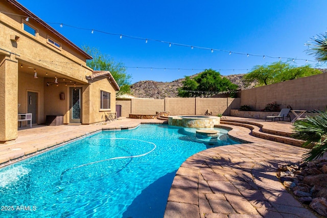 view of swimming pool featuring a patio area, a pool with connected hot tub, a mountain view, and a fenced backyard