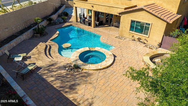 view of swimming pool featuring a patio area, a pool with connected hot tub, and a fenced backyard