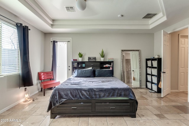 bedroom with multiple windows, a tray ceiling, and visible vents