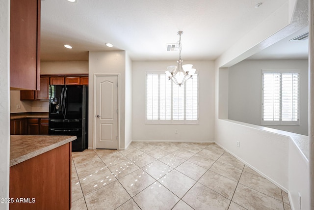 kitchen with light tile patterned floors, freestanding refrigerator, a chandelier, and visible vents
