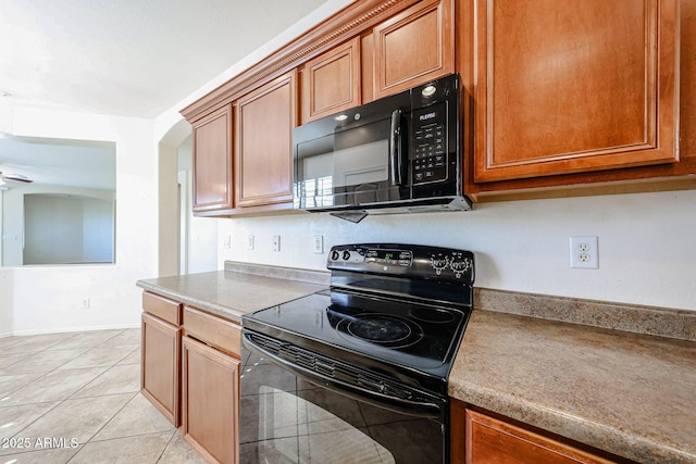 kitchen with arched walkways, black appliances, brown cabinets, and light tile patterned flooring