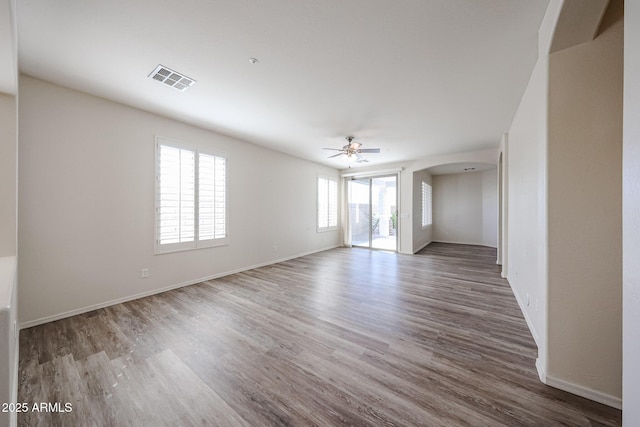 spare room featuring arched walkways, a ceiling fan, visible vents, and wood finished floors