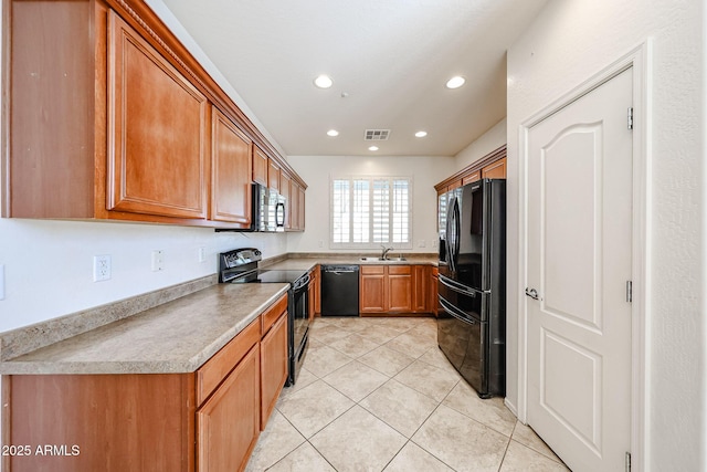 kitchen featuring visible vents, light tile patterned flooring, brown cabinets, a sink, and black appliances
