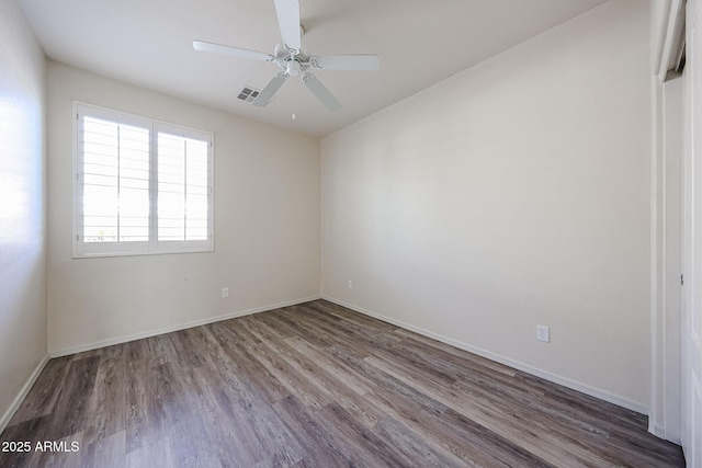 unfurnished room with visible vents, a ceiling fan, baseboards, and wood finished floors
