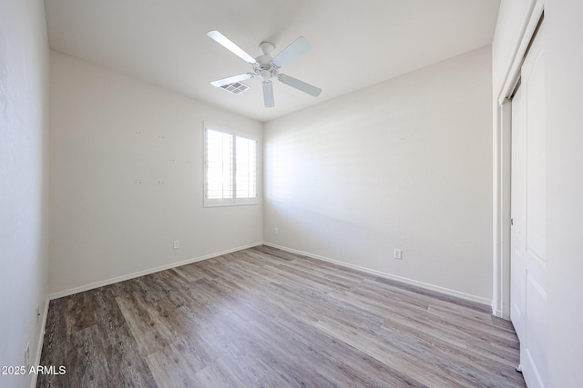 unfurnished room featuring baseboards, ceiling fan, visible vents, and wood finished floors