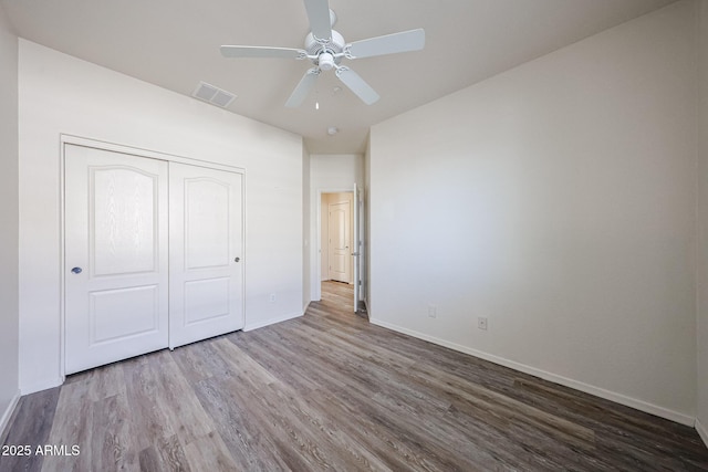 unfurnished bedroom featuring baseboards, visible vents, and wood finished floors
