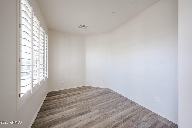 unfurnished room featuring a healthy amount of sunlight, wood finished floors, and visible vents