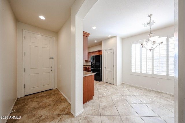 interior space featuring visible vents, light tile patterned flooring, baseboards, arched walkways, and a notable chandelier