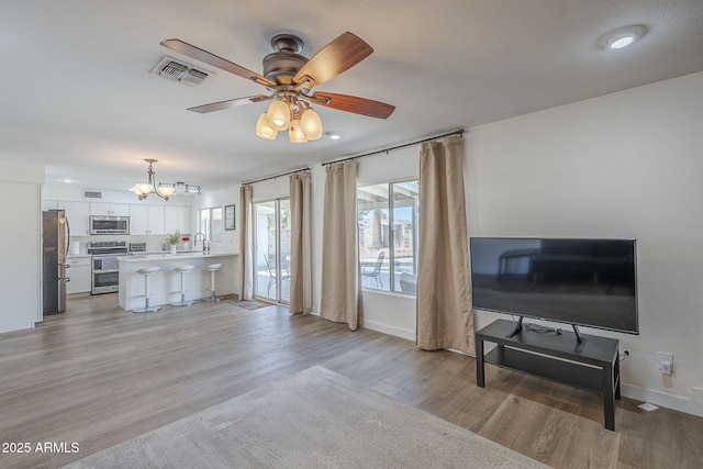 12234 S Pewaukee St, Phoenix, AZ 85044 - living area featuring light wood finished floors, a ceiling fan, and a chandelier