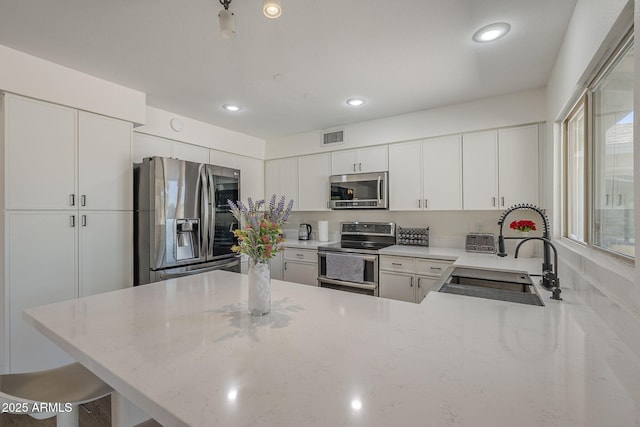 12234 S Pewaukee St, Phoenix, AZ 85044 - kitchen featuring appliances with stainless steel finishes, a peninsula, light stone counters, recessed lighting, and white cabinets