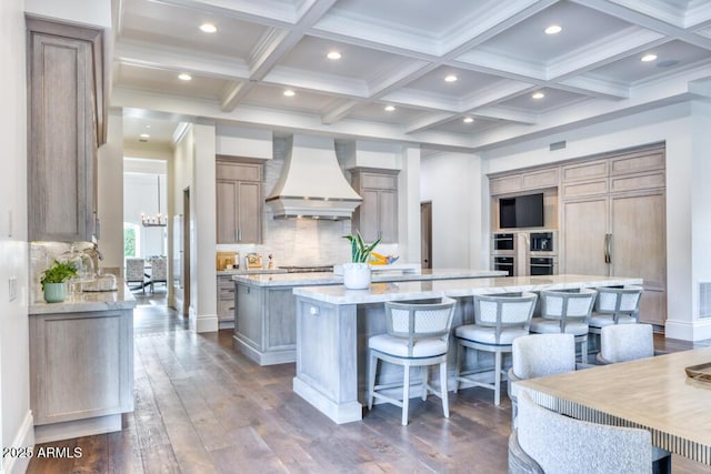 kitchen featuring a breakfast bar, beamed ceiling, a large island, backsplash, and premium range hood