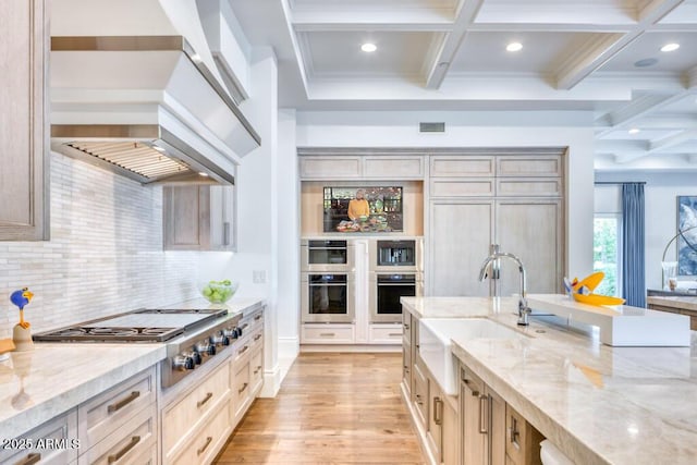 kitchen featuring visible vents, premium range hood, coffered ceiling, and a sink