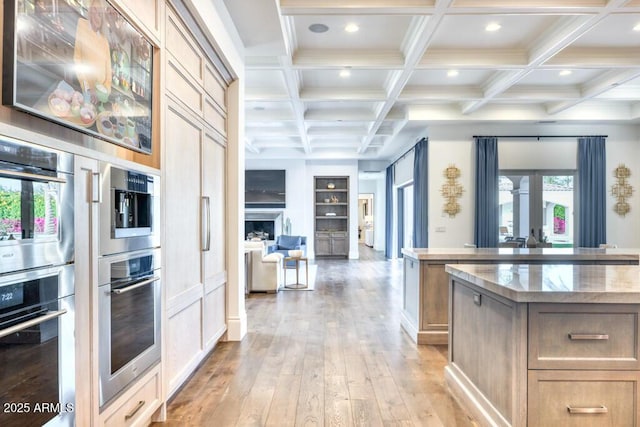 kitchen with recessed lighting, beam ceiling, a wealth of natural light, light wood-style flooring, and double oven
