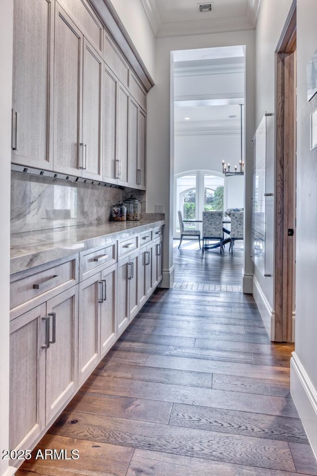 bar featuring tasteful backsplash, crown molding, visible vents, arched walkways, and dark wood finished floors