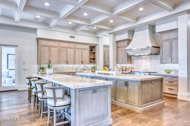 kitchen with tasteful backsplash, custom range hood, beam ceiling, a large island, and wood finished floors