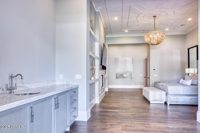 bathroom with wood finished floors, built in shelves, a sink, a notable chandelier, and crown molding