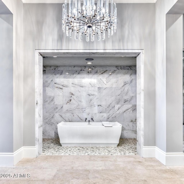 bathroom with baseboards, a freestanding bath, and an inviting chandelier