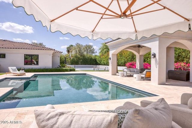 view of pool featuring a patio area, a fenced in pool, outdoor lounge area, a ceiling fan, and a hot tub