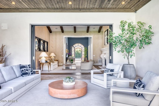 living area with wood finished floors, beamed ceiling, ornamental molding, and wood ceiling