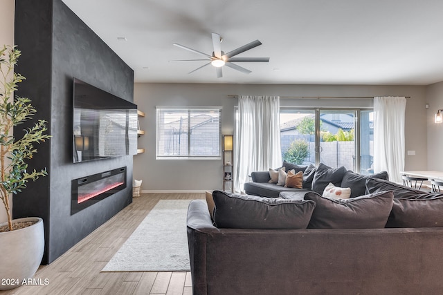 living room featuring a fireplace, light hardwood / wood-style floors, and ceiling fan