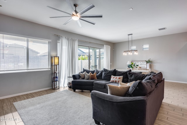 living room featuring light hardwood / wood-style floors and ceiling fan with notable chandelier