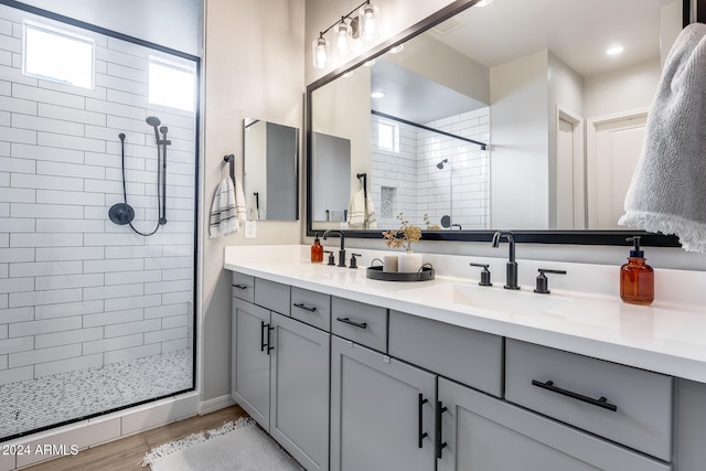 bathroom with wood-type flooring, vanity, and tiled shower