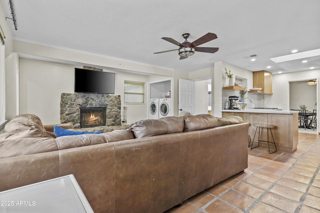 living area with a skylight, a ceiling fan, independent washer and dryer, a stone fireplace, and recessed lighting