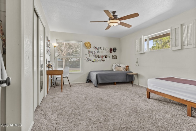 carpeted bedroom with a textured ceiling, ceiling fan, and baseboards