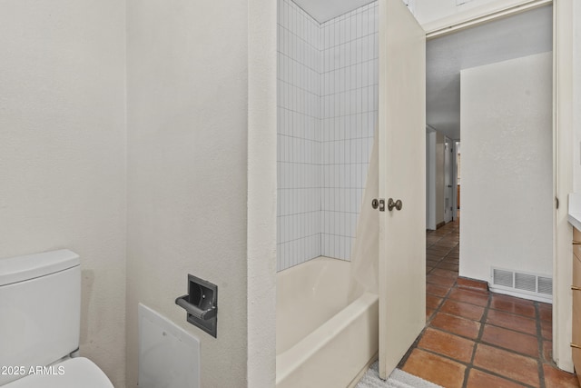 bathroom featuring toilet, shower / bath combination, and visible vents