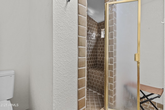 bathroom with toilet and a tile shower