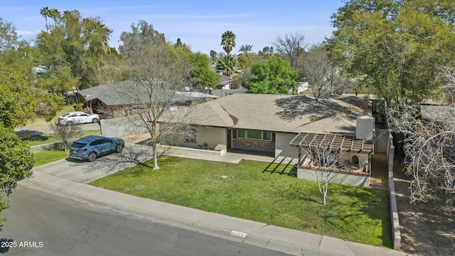 view of front facade with driveway, stone siding, and a front yard