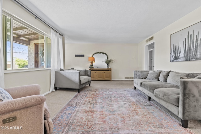 carpeted living room featuring visible vents, a textured ceiling, and baseboards