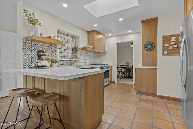 kitchen with a peninsula, a skylight, appliances with stainless steel finishes, backsplash, and open shelves