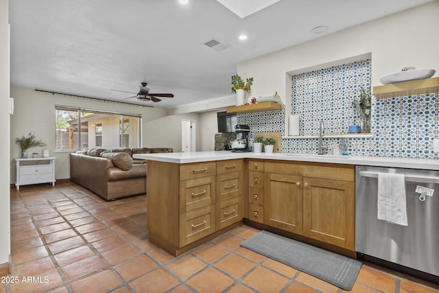 kitchen featuring visible vents, dishwasher, a peninsula, light countertops, and backsplash