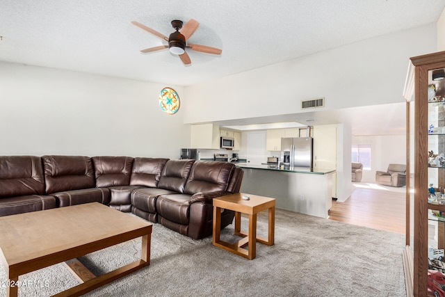 living room with a textured ceiling, light hardwood / wood-style floors, and ceiling fan