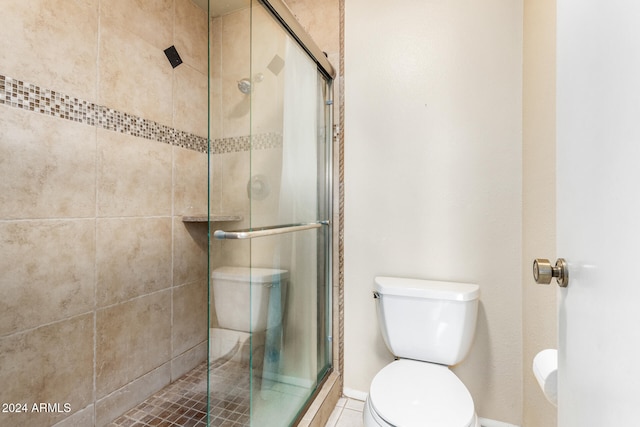 bathroom with tile patterned flooring, toilet, and a shower with door