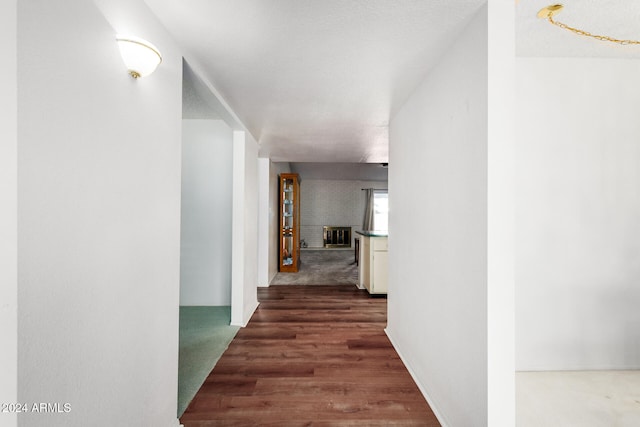 corridor with a textured ceiling and dark hardwood / wood-style floors